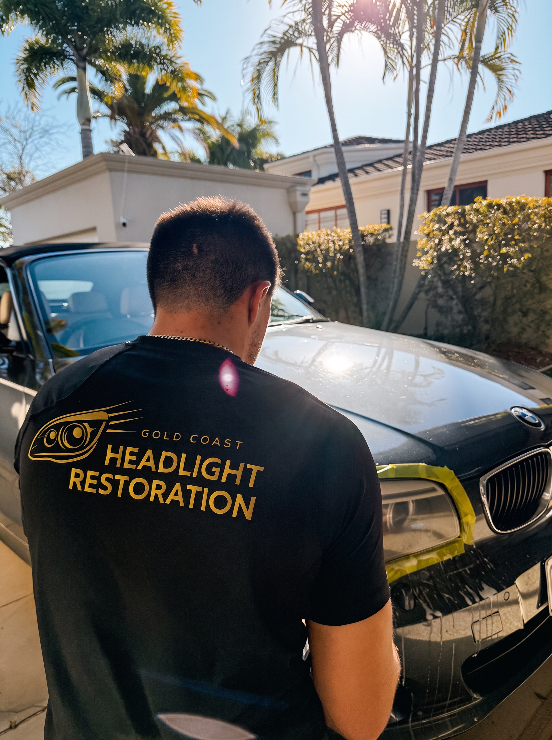 Technician in Gold Coast Headlight Restoration uniform restoring a car headlight
